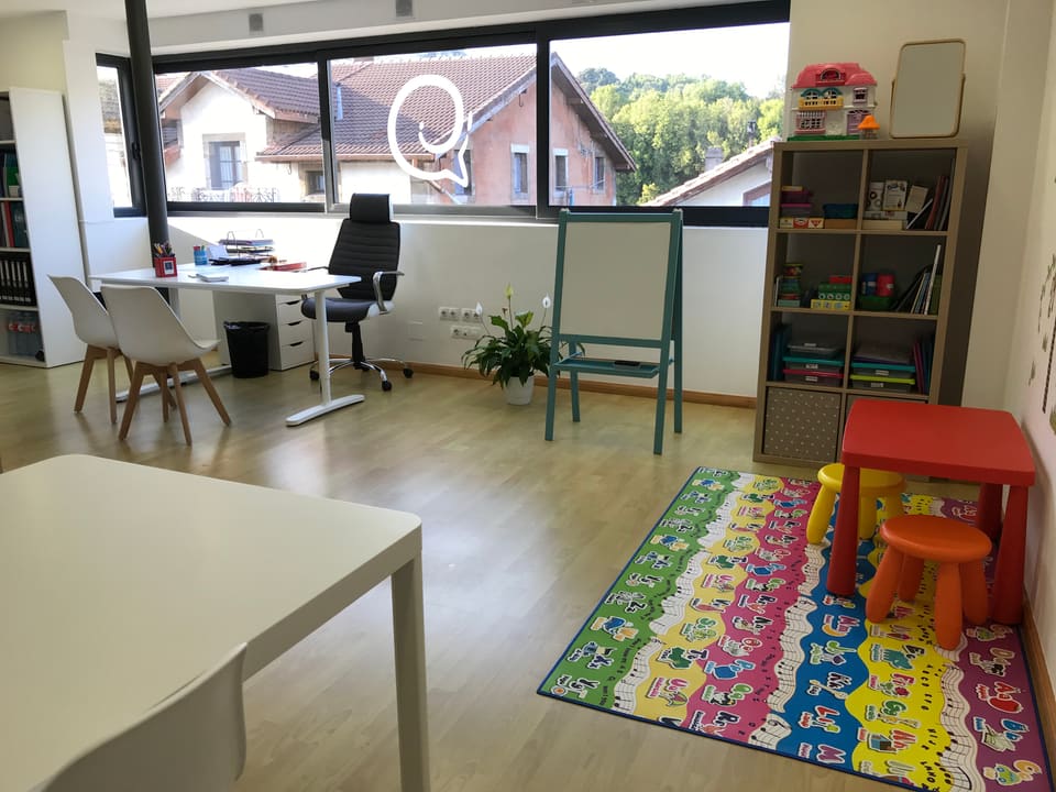 Sala de la consulta de logopedia en Solares, con mesa de trabajo y rincón infantil junto al ventanal