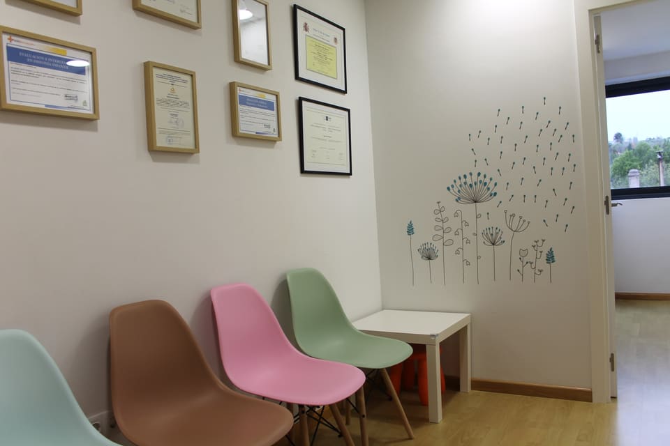 Sala de espera con sillas de colores y una mesa infantil